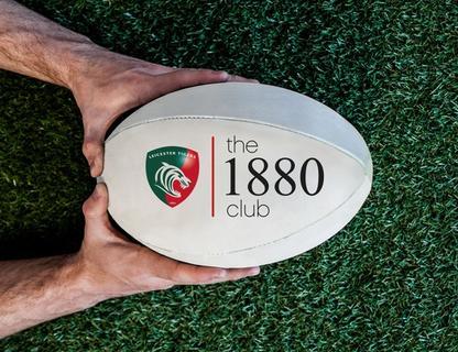 Man holding rugby ball with the 1880 club logo printed on it.
